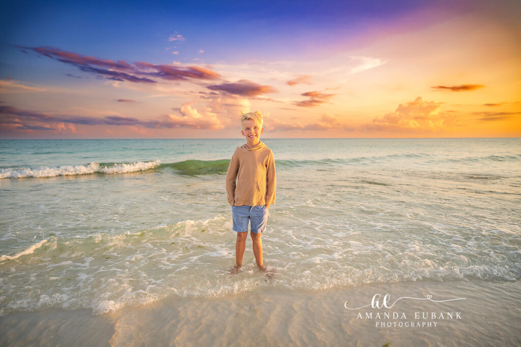 A senior guy standing in the surf at golden sunset, photographed by a Bradenton senior photographer