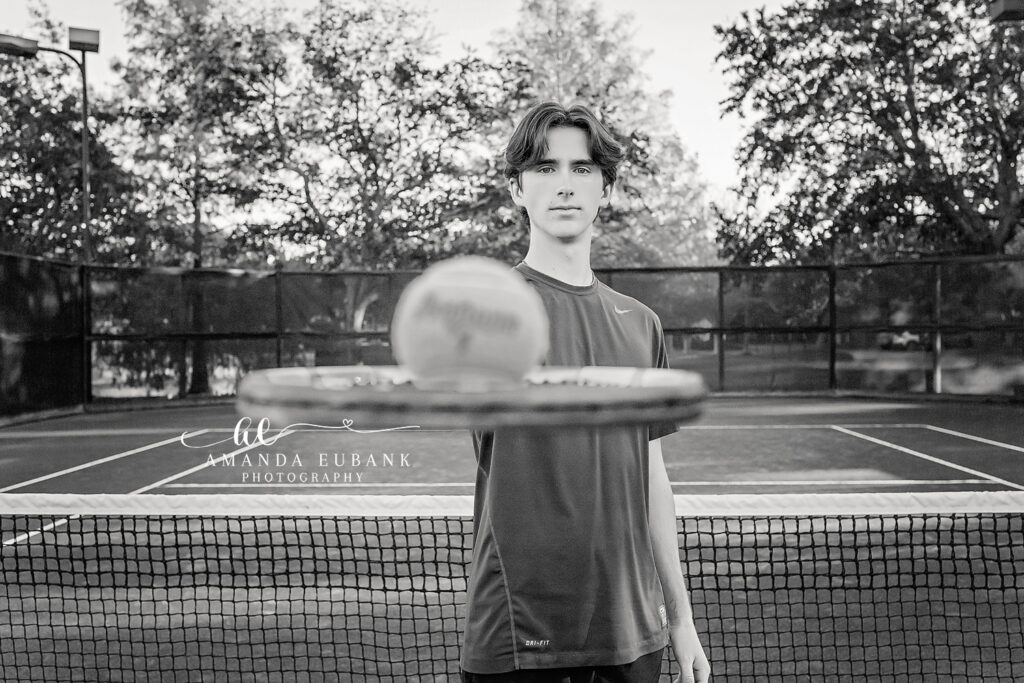 A black and white portrait of a senior guy leaning on the net of a tennis court in Indian Rocks Beach, Florida