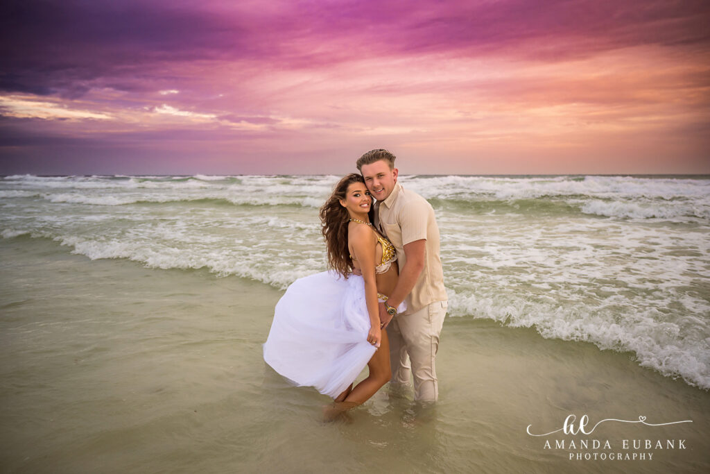 A mother in white wading with her children beneath a purple sky during a Lido Key family photography session