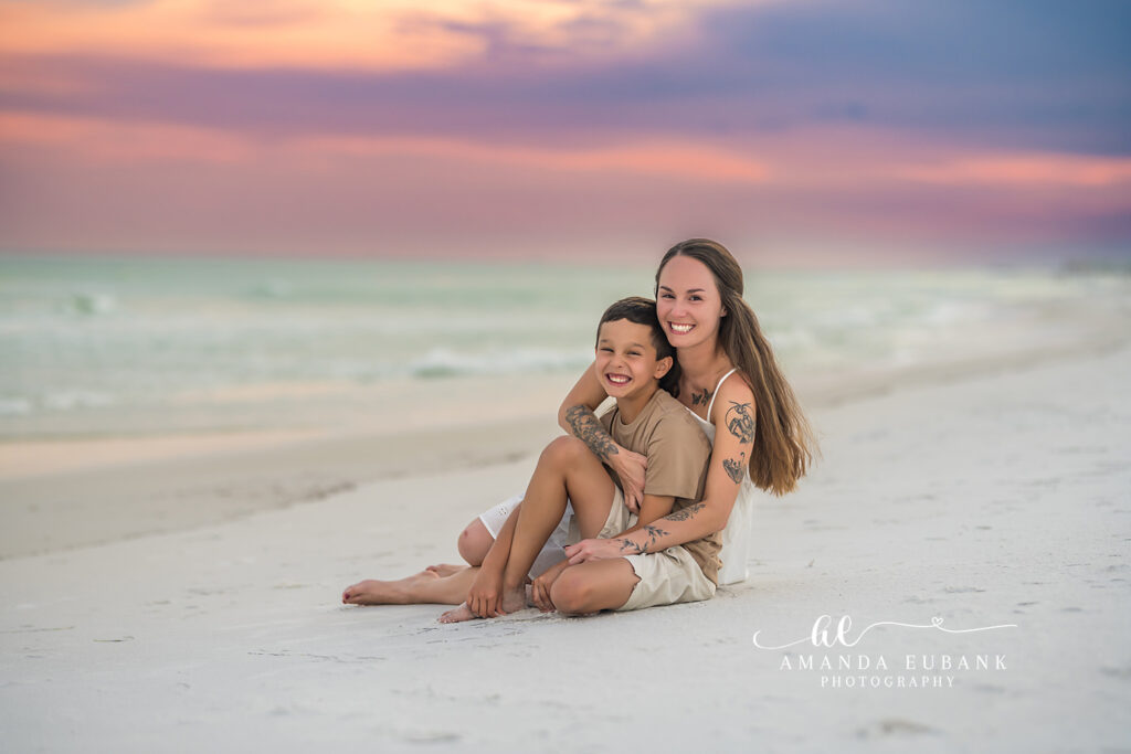 A couple cuddled together seated on the sand in muted evening tones on Longboat Key, Florida