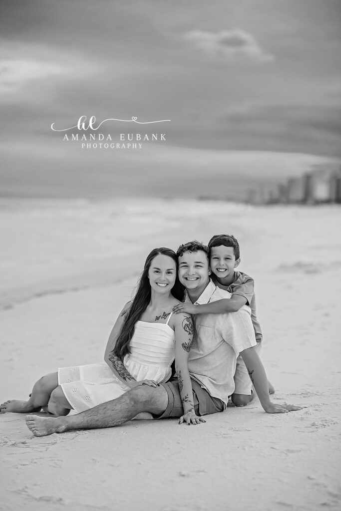 A black and white portrait of a family of four seated on the dune, photographed by a Longboat Key family photographer
