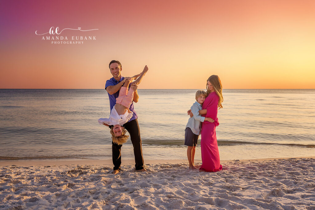 Parents with their children at the shoreline, mom in a red dress in golden light, photographed by a Palm Harbor family photographer