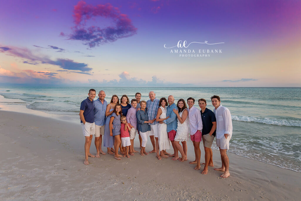 An extended family in blues and whites gathered beneath a purple sky, photographed by a Siesta Key family photographer