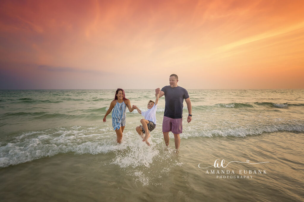 A family walking and playing in golden evening mist during a St. Pete Beach family photography session