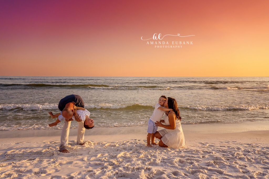 Parents swinging their children on the sand in pastel light, photographed by a St. Petersburg family photographer