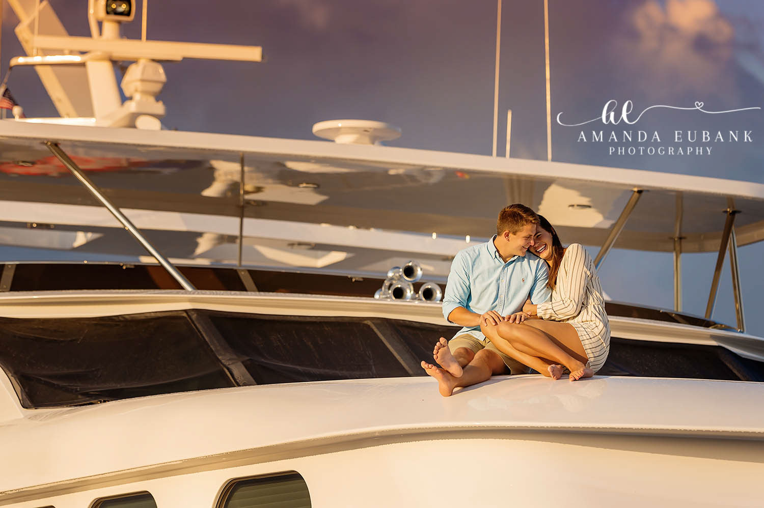 Engagement Portraits on a Yacht | Engagement Photographer in Tampa, Florida Engagement photos in Tampa, FL showing a couple curled up together on the bow of a white yacht at golden hour.