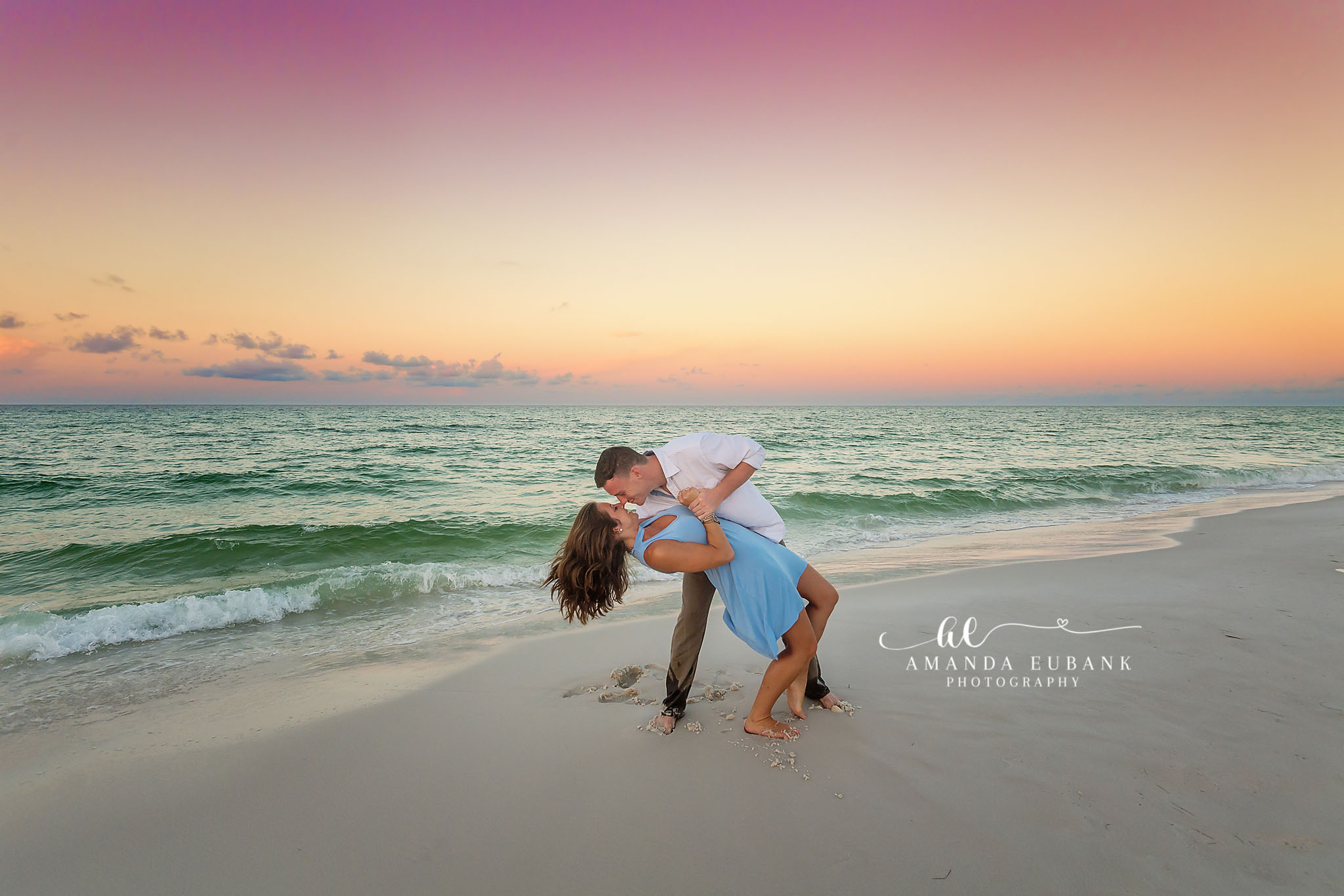 Dip Kiss at the Water’s Edge — Tampa Bay Engagement Photography A man dipping his fiancee for a kiss on the shoreline as the sun goes down — beach engagement photography in Tampa Bay.