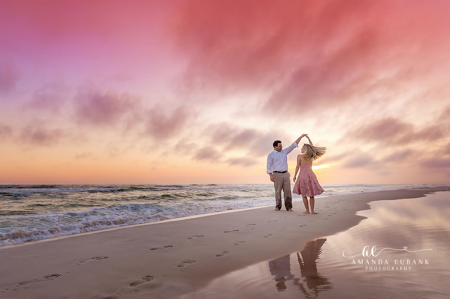 Reflections on Wet Sand — Tampa Bay Engagement Photography A couple dancing on mirror-smooth wet sand beneath a soft pink sunset — beach engagement photography in Tampa Bay.