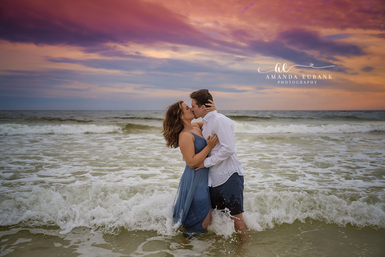 Kiss in the Waves | Tampa Beach Engagement Photography Tampa engagement photographer captures a couple kissing knee-deep in the waves under a bank of purple clouds.