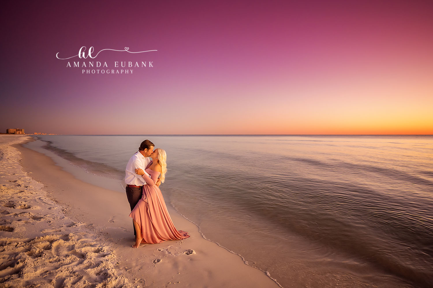 Peach Gown at Golden Hour — Tampa Bay Engagement Photography A couple embracing on the shoreline in a flowing peach gown under a hot pink sky — beach engagement photography in Tampa Bay.