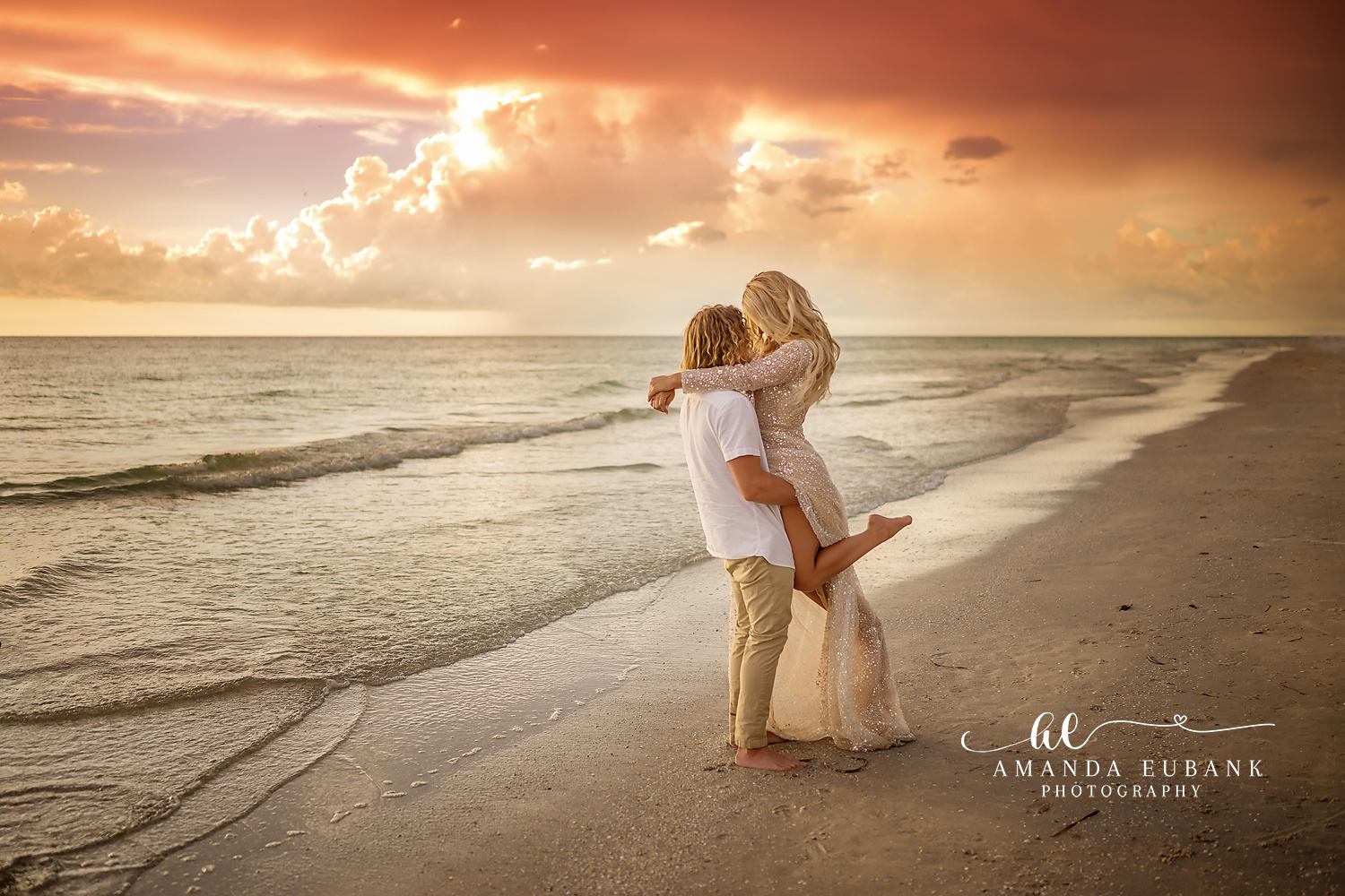 Sunbeams and a Sunset Lift | Engagement Photographer in Tampa, Florida Engagement photos in Tampa, FL showing a man lifting his fiancee on the shoreline as sunbeams pour through the clouds.
