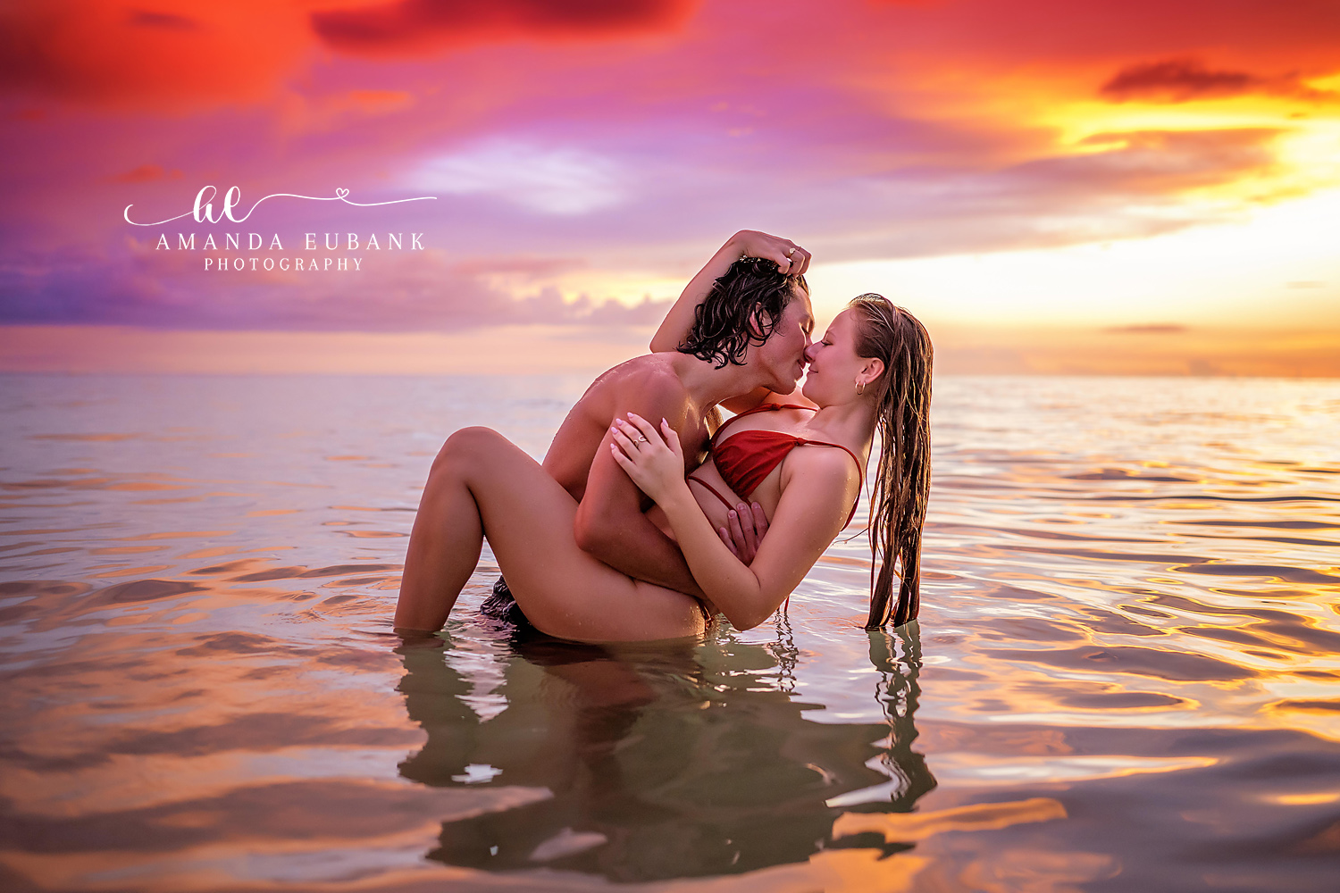 Sunset Session in the Shallows | Tampa Engagement Photographer A couple lying together in the warm shallows under a violet and orange sky during a Tampa engagement photography session.