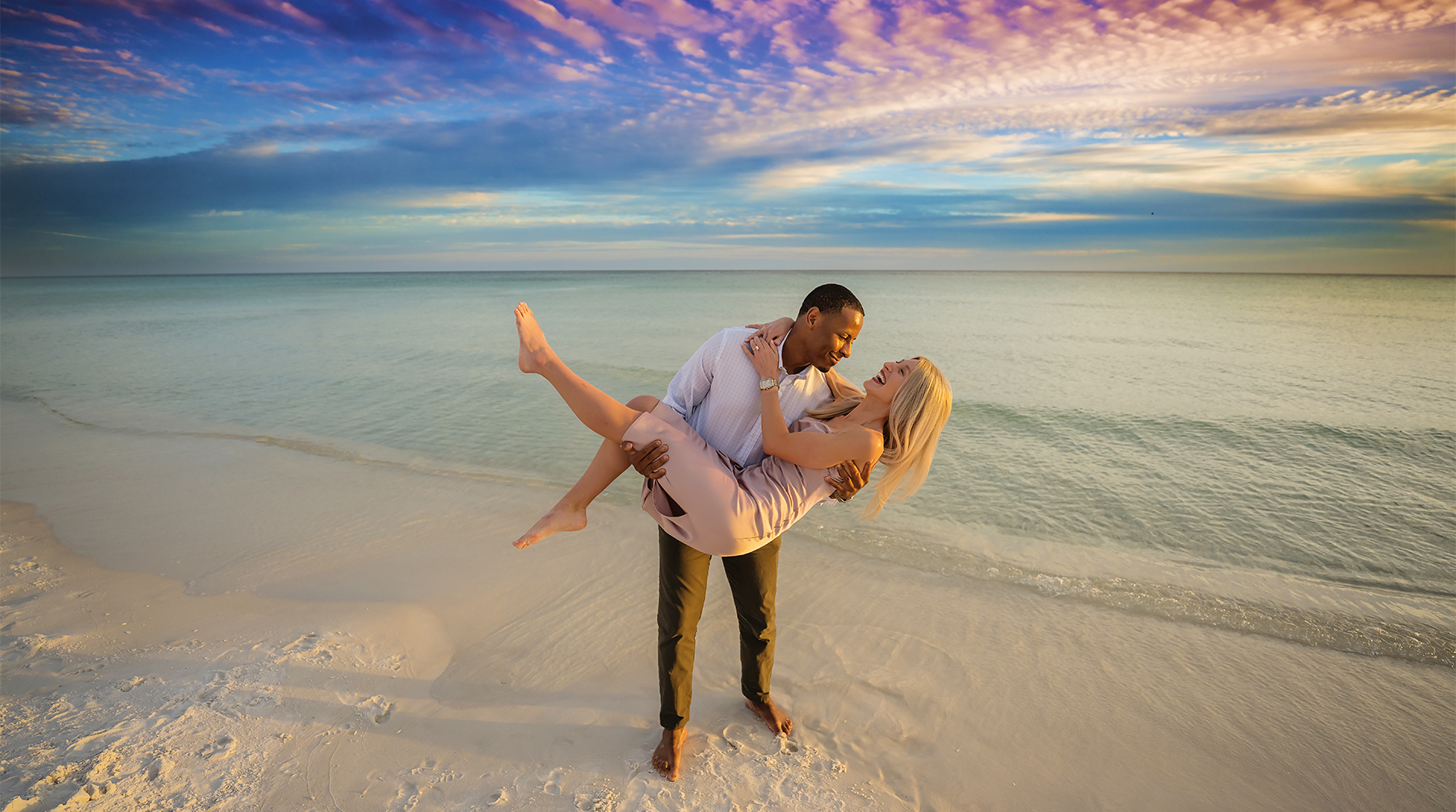 Sunset Carry by the Water — Tampa Bay Engagement Photography A man carrying his fiancee as she leans back laughing above the turquoise shallows — beach engagement photography in Tampa Bay.