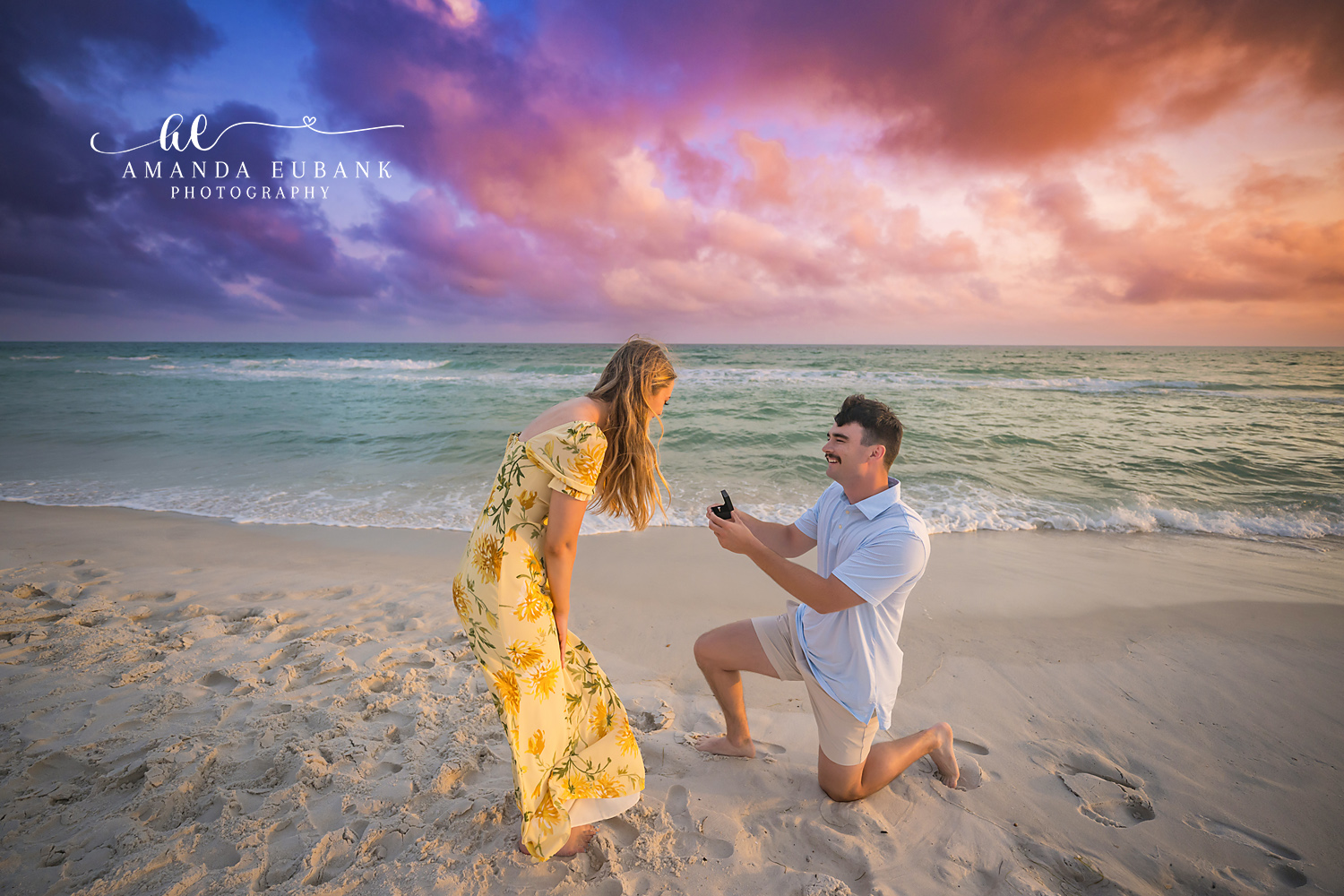 Leaning Into the Proposal | Tampa Engagement Photographer She leans toward him as he holds out the open ring box under lavender clouds during a Tampa engagement photography session.