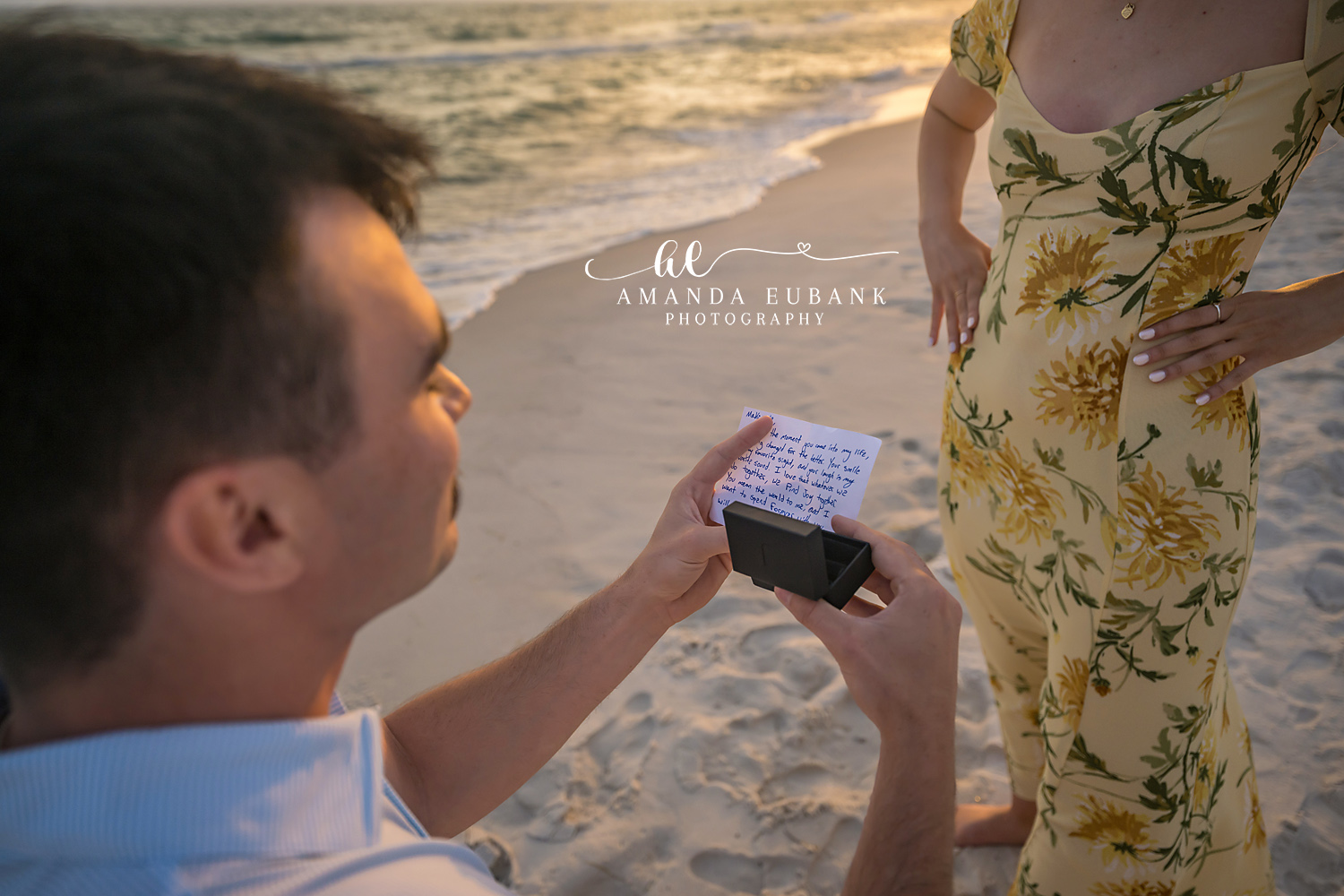 The Ring Box — Tampa, FL Engagement Session A close crop of the open ring box held out toward her yellow floral dress at a Gulf beach engagement session near Tampa, Florida.