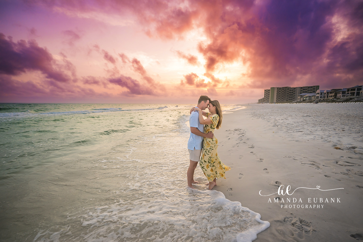 Waves at Their Feet — Tampa Bay Engagement Photography A couple embracing ankle-deep in the waves beneath a violet cloudscape — beach engagement photography in Tampa Bay.
