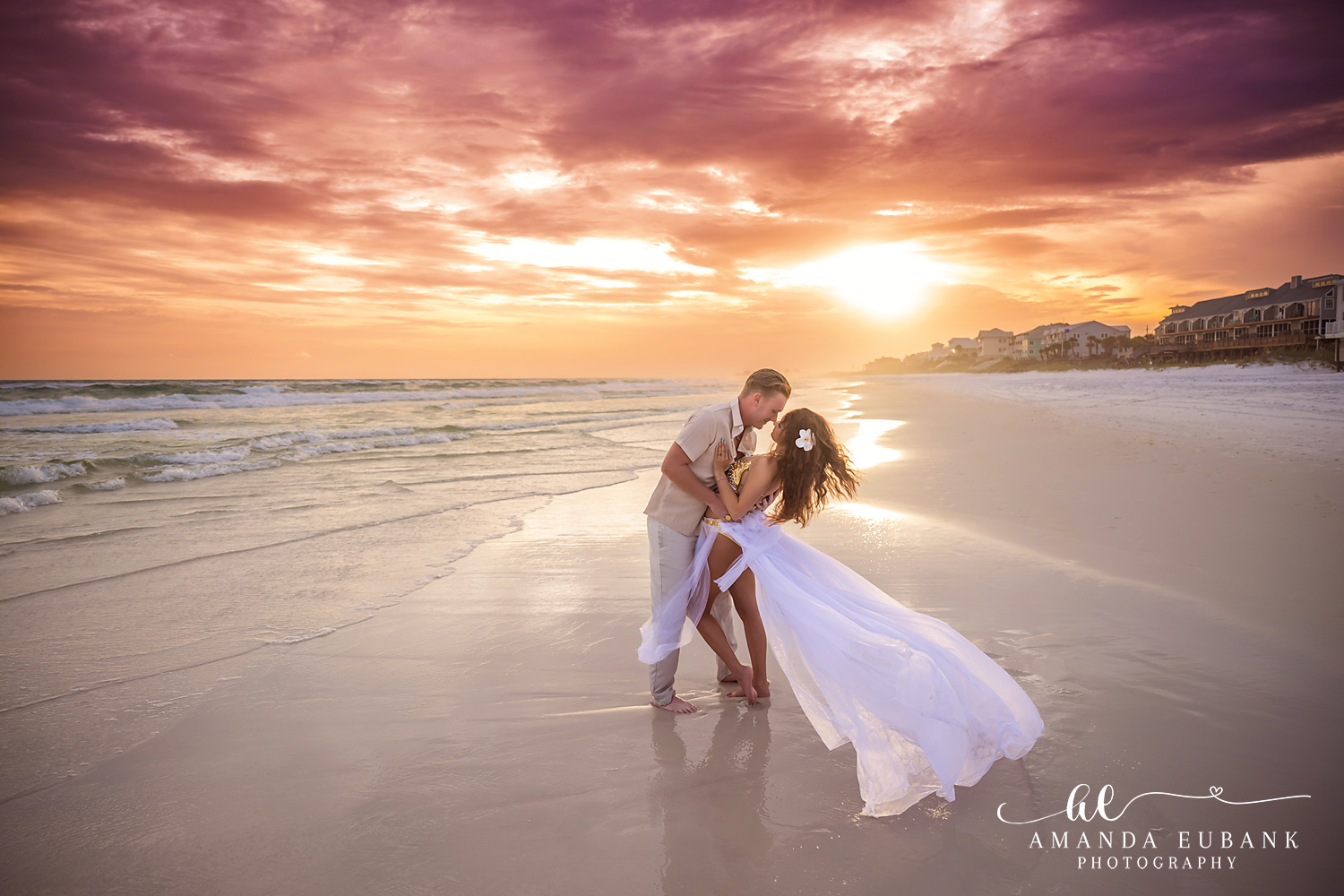 Dip Kiss in the Sunset Glow | Engagement Photographer in Tampa, Florida Engagement photos in Tampa, FL showing a dip kiss on reflective wet sand with the sun setting behind the coastline.
