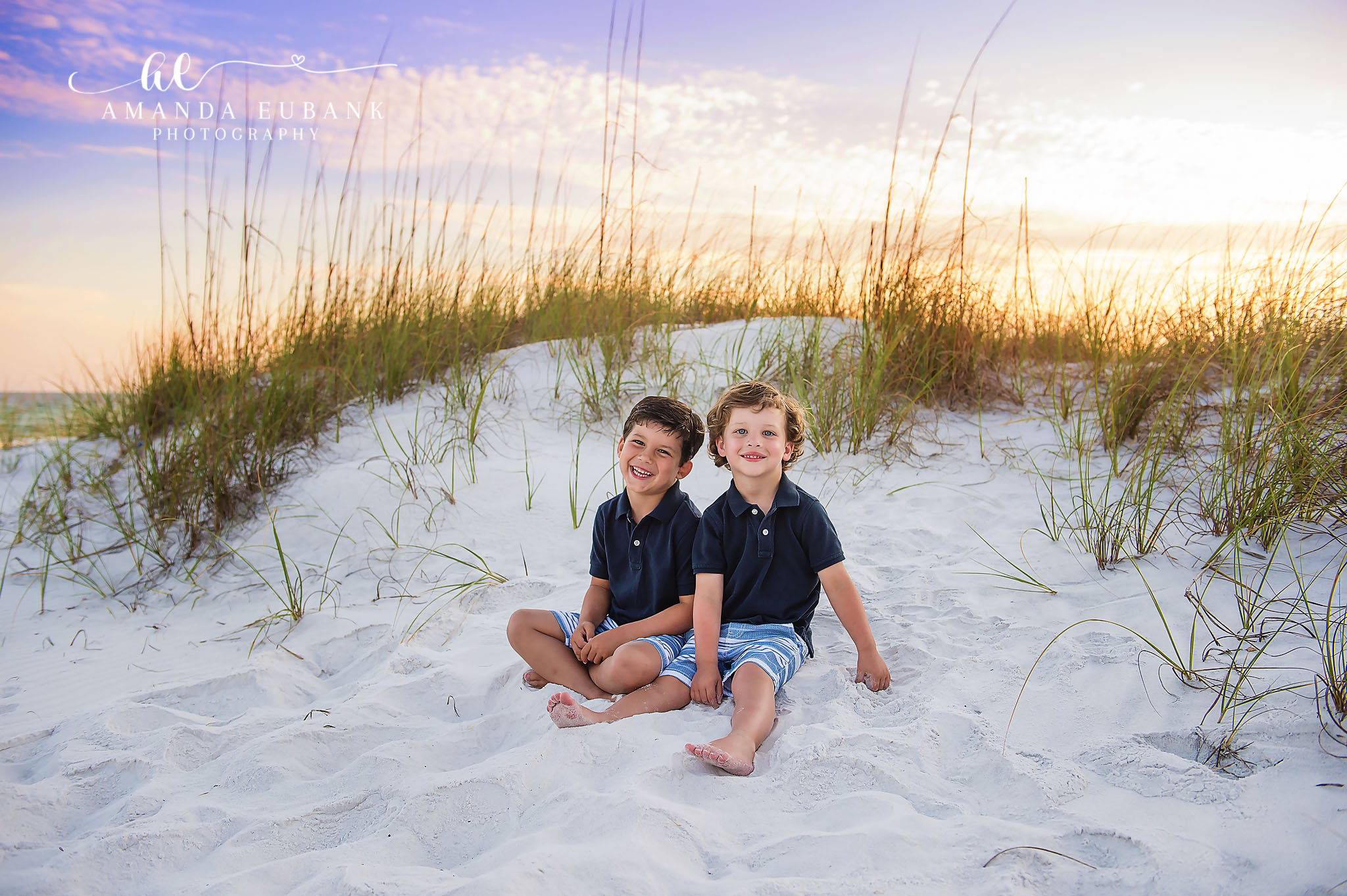 Brothers on the Dune — Tampa Bay Children’s Photography Two brothers in navy polos sitting side by side on a white sand dune at a beach kids session in Tampa, FL.