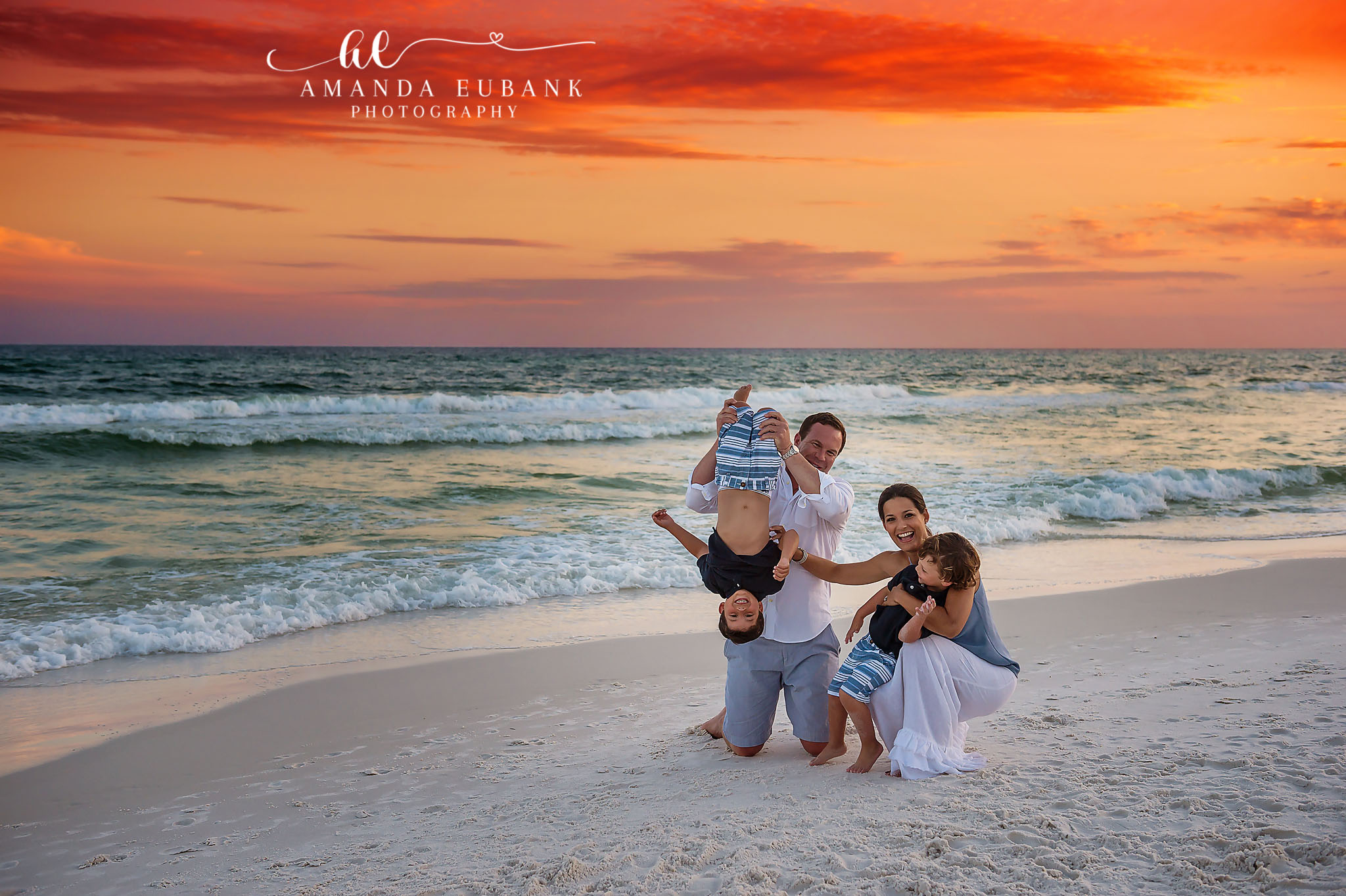 Upside Down at Sunset — Tampa Bay Family Portraits A dad holding his child upside down while the family laughs under an orange sky — beach family photography in Tampa Bay.