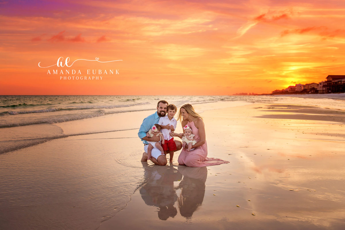 Reflections at Sunset | Family Photographer in Tampa, Florida Family beach portraits in Tampa, FL showing a family of five seated on reflective wet sand as the sky turns brilliant orange.