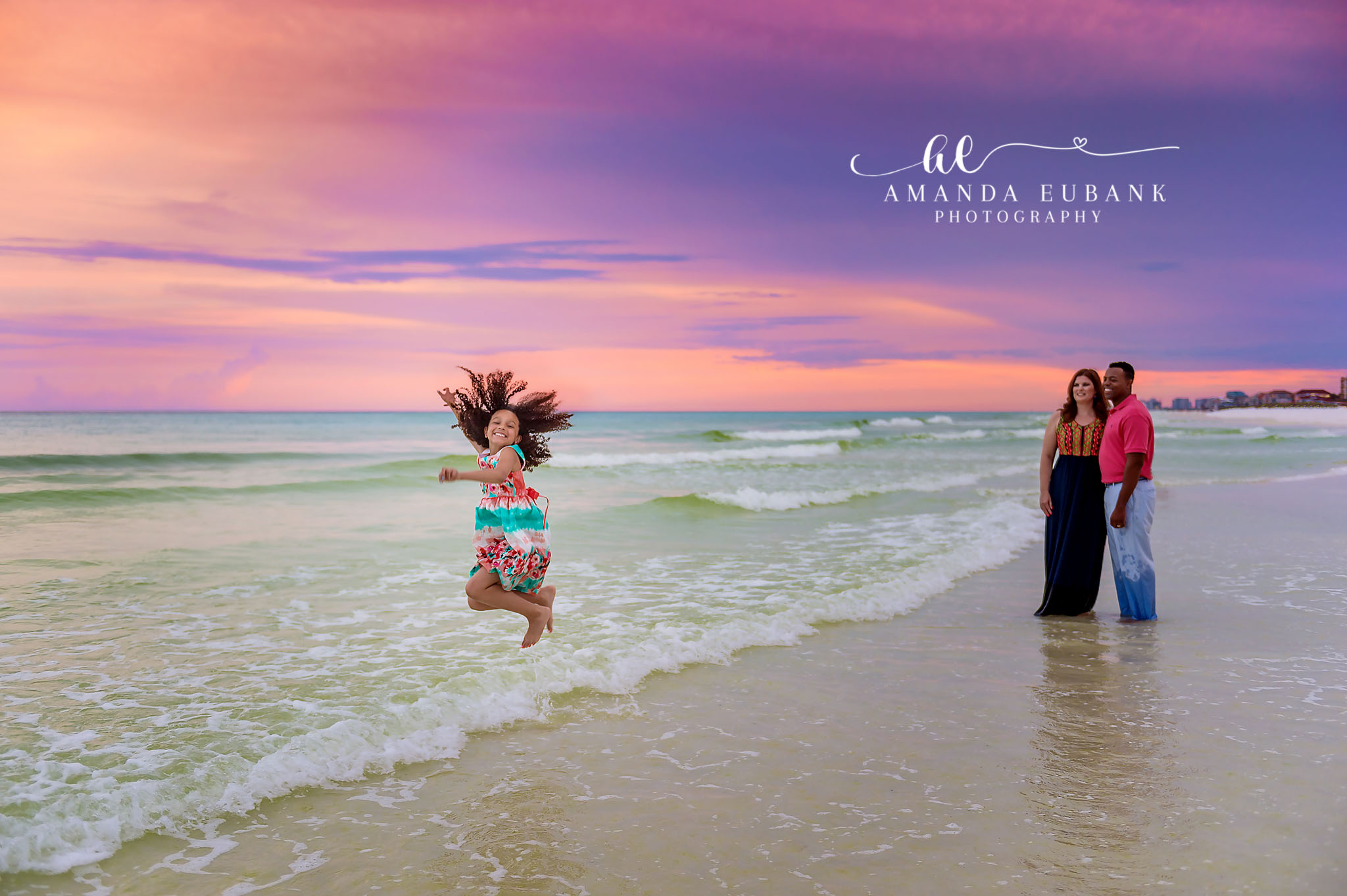 Jumping on the Shoreline | Family Photographer in Tampa, Florida Family beach portraits in Tampa, FL showing a girl leaping into the air on the shoreline while her family watches.