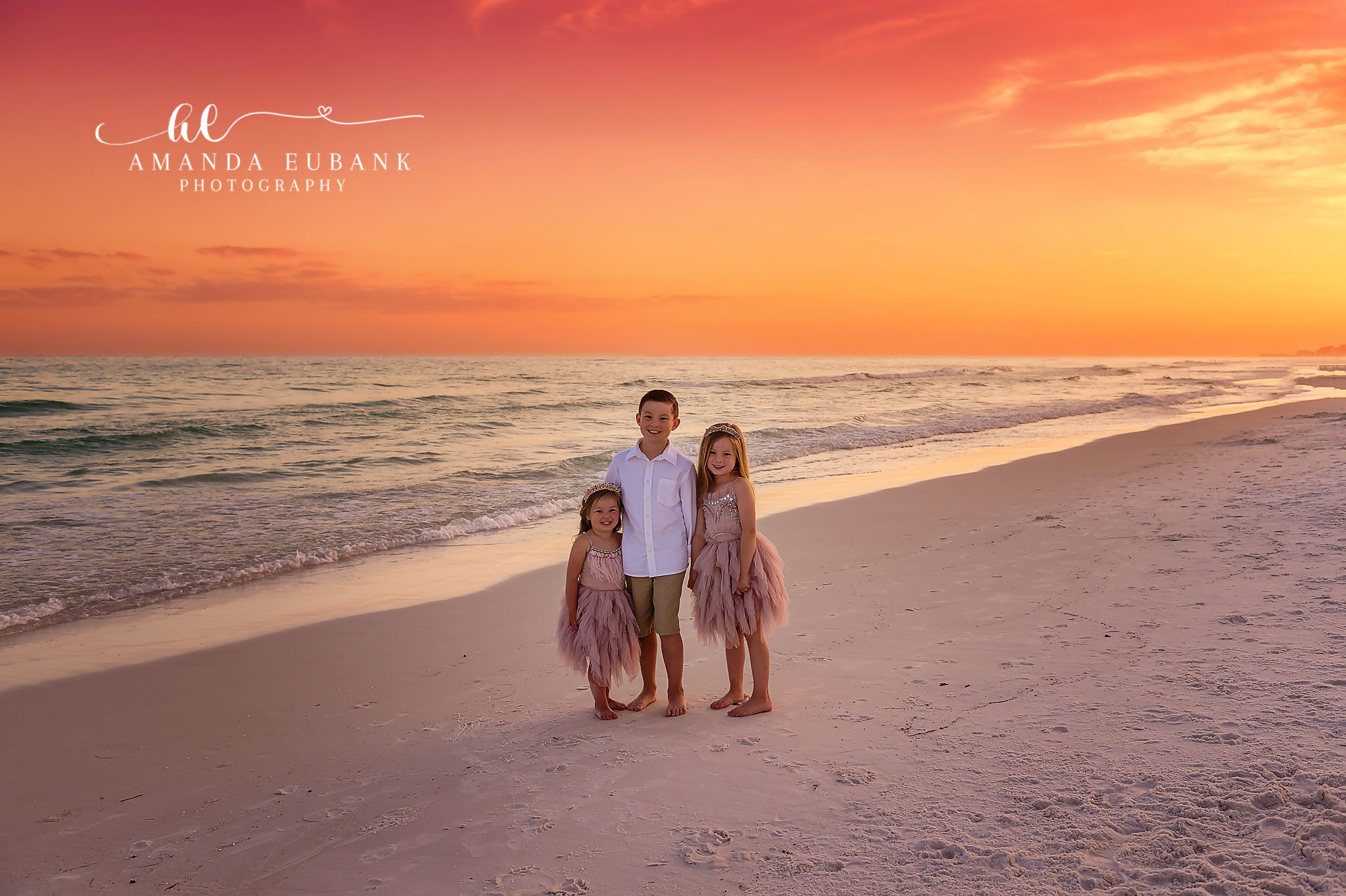 Family of Four at Sunset — Tampa Bay Family Portraits A family of four standing together on the beach as the sky glows orange — beach family photography in Tampa Bay.