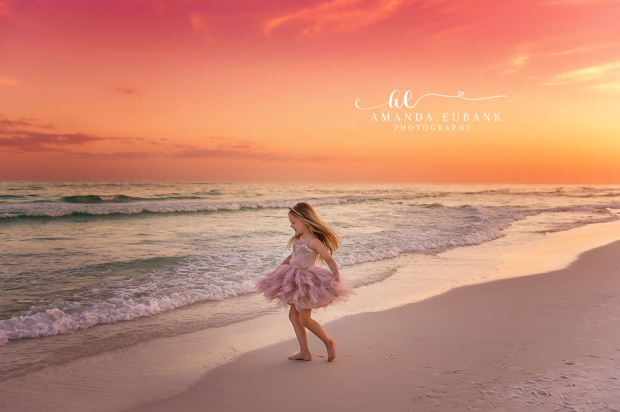 Tulle in the Surf | Kids Beach Portraits in Tampa, FL Tampa children’s photographer captures a little girl in blush tulle walking through the surf under an orange sky.
