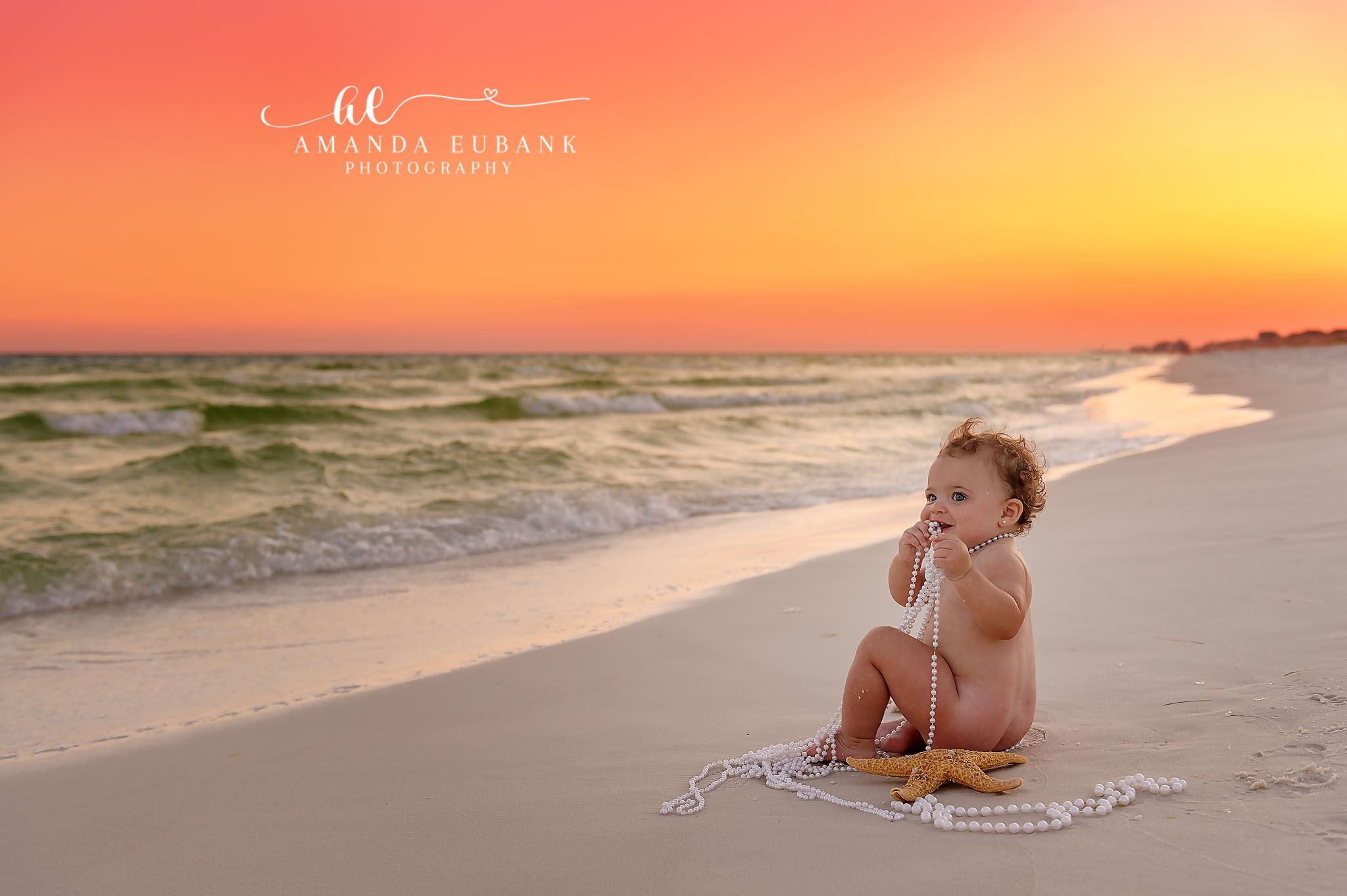Baby Milestone on the Beach | Tampa Baby & Milestone Photographer A baby sitting on a blanket on the sand as the sky turns deep orange during a baby milestone session in Tampa, Florida.