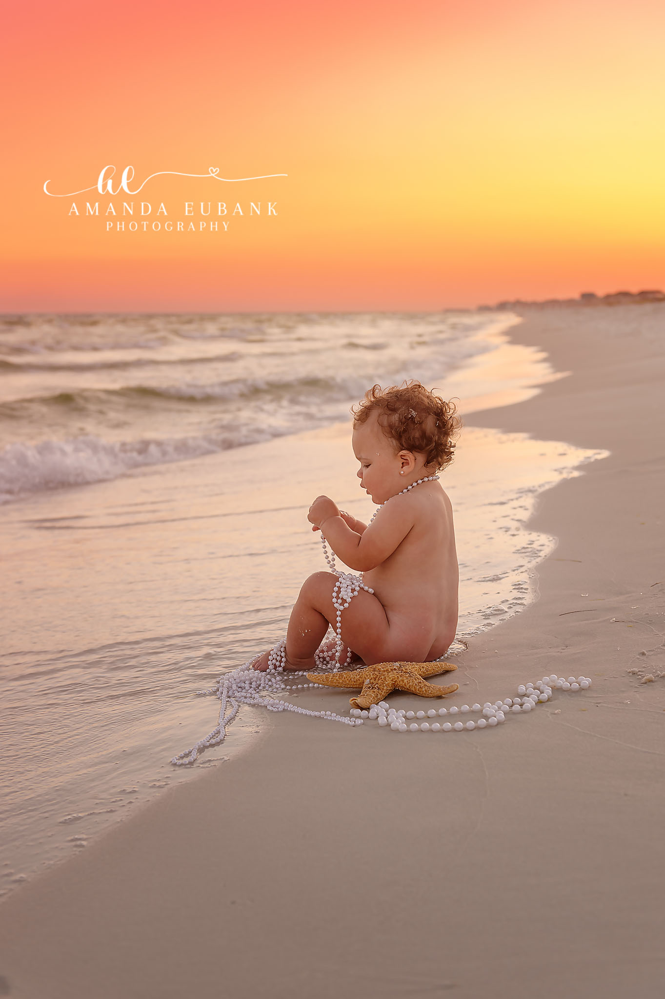 Baby at the Water’s Edge — Tampa Bay Baby Photography A baby sitting at the edge of the surf on a wide pastel-lit beach at a beach milestone session in Tampa, FL.