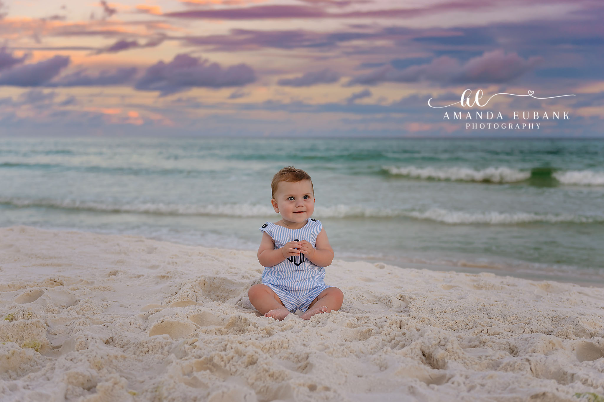 Baby Boy on White Sand | Tampa Baby & Milestone Photographer A baby boy in a blue romper sitting on white sand with the Gulf behind him during a baby milestone session in Tampa, Florida.