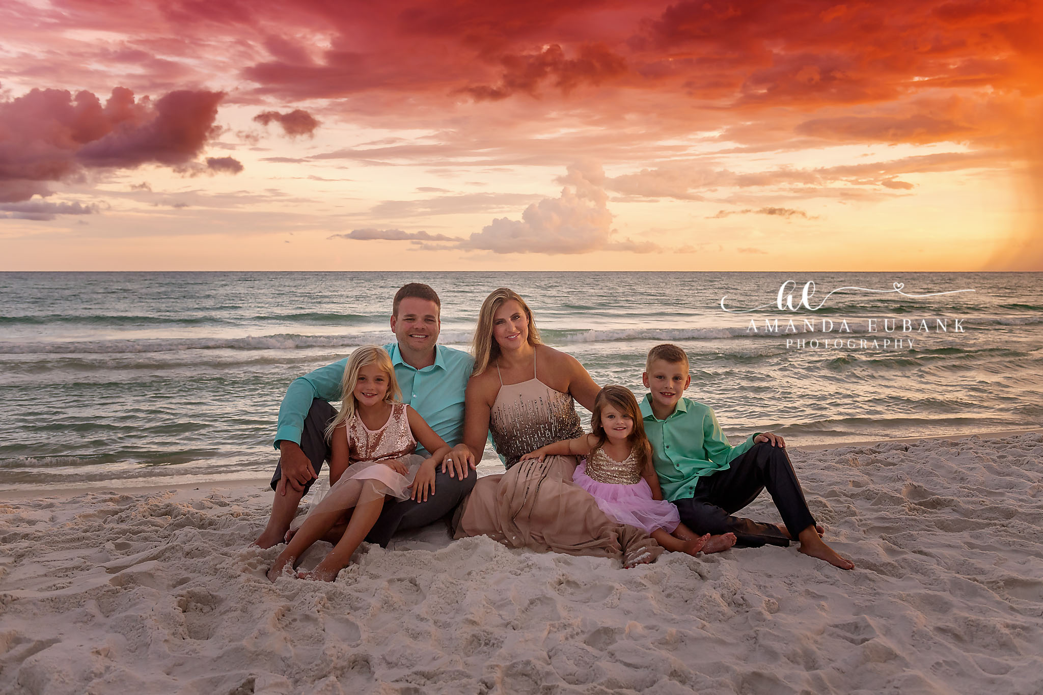 Family of Six on the Sand | Tampa Family Photographer A family of six sitting together on the sand beneath a coral sky during a Tampa family photography session.