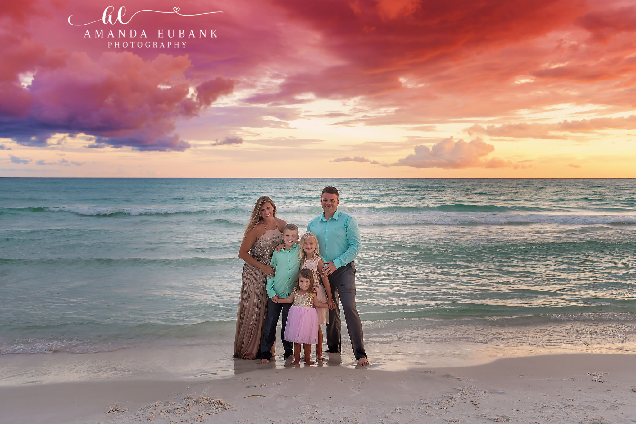 Family in the Shallow Surf — Tampa, FL Family Session A family of five standing in the shallow surf under dramatic sunset clouds at a beach family session near Tampa, Florida.