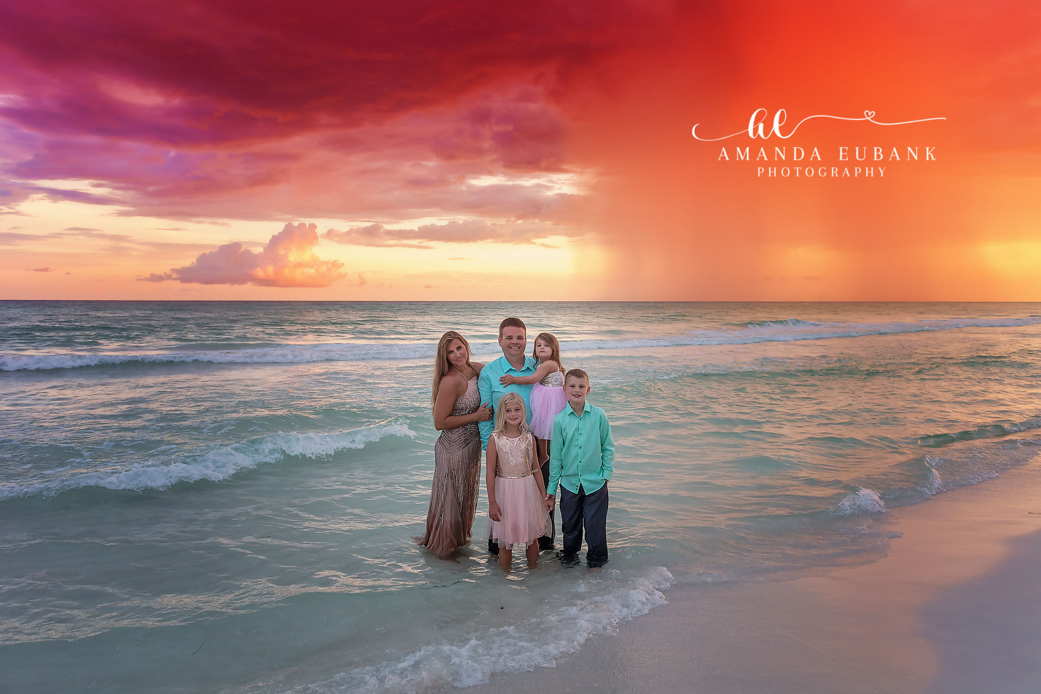 Five at the Water’s Edge — Tampa Bay Family Portraits A family of five at the water's edge as purple and orange light spreads overhead — beach family photography in Tampa Bay.