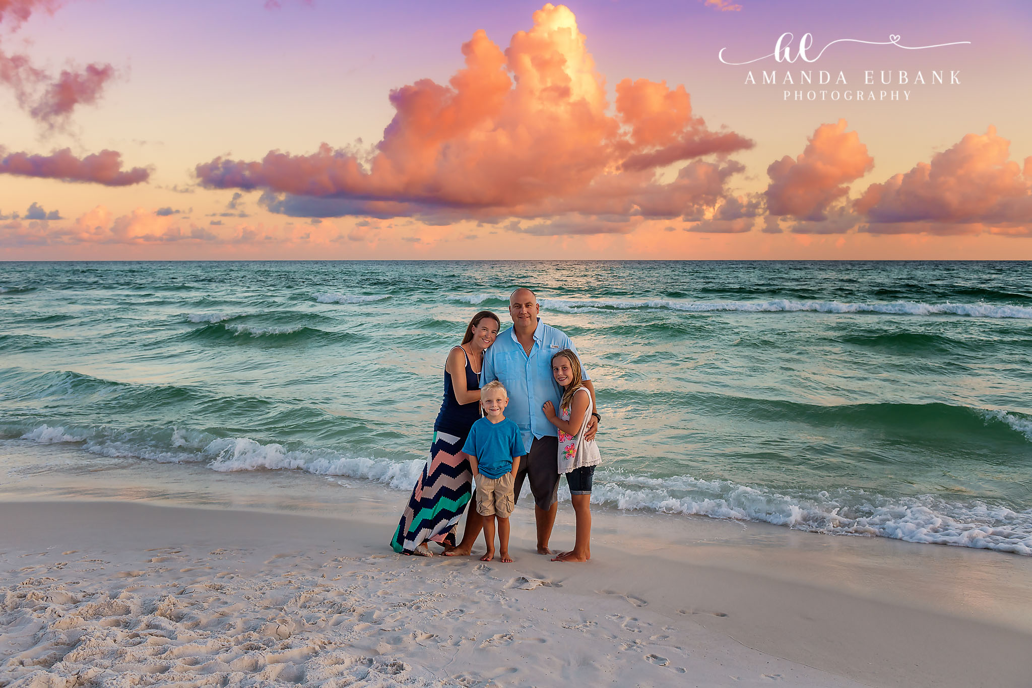 Family Under Towering Clouds | Tampa Beach Family Photography Tampa family photographer captures a family of five standing in the surf beneath towering pink cumulus clouds.
