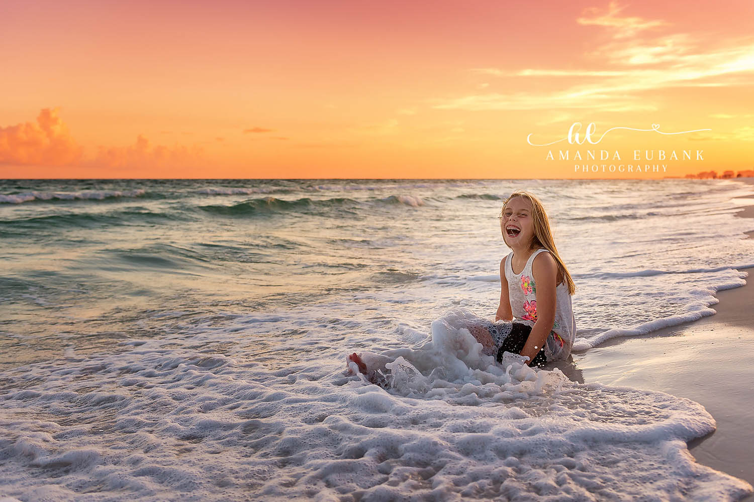 Laughing in the Surf | Kids Beach Portraits in Tampa, FL Tampa children’s photographer captures a young girl sitting in the surf laughing as a wave rolls in around her.