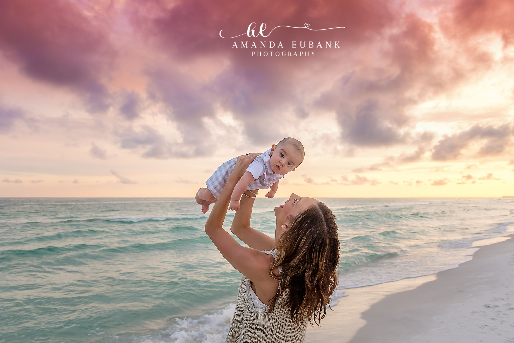 Baby Lifted to the Sky | Tampa Family Photographer A mother lifting her baby overhead on the beach against pastel sunset clouds during a Tampa family photography session.