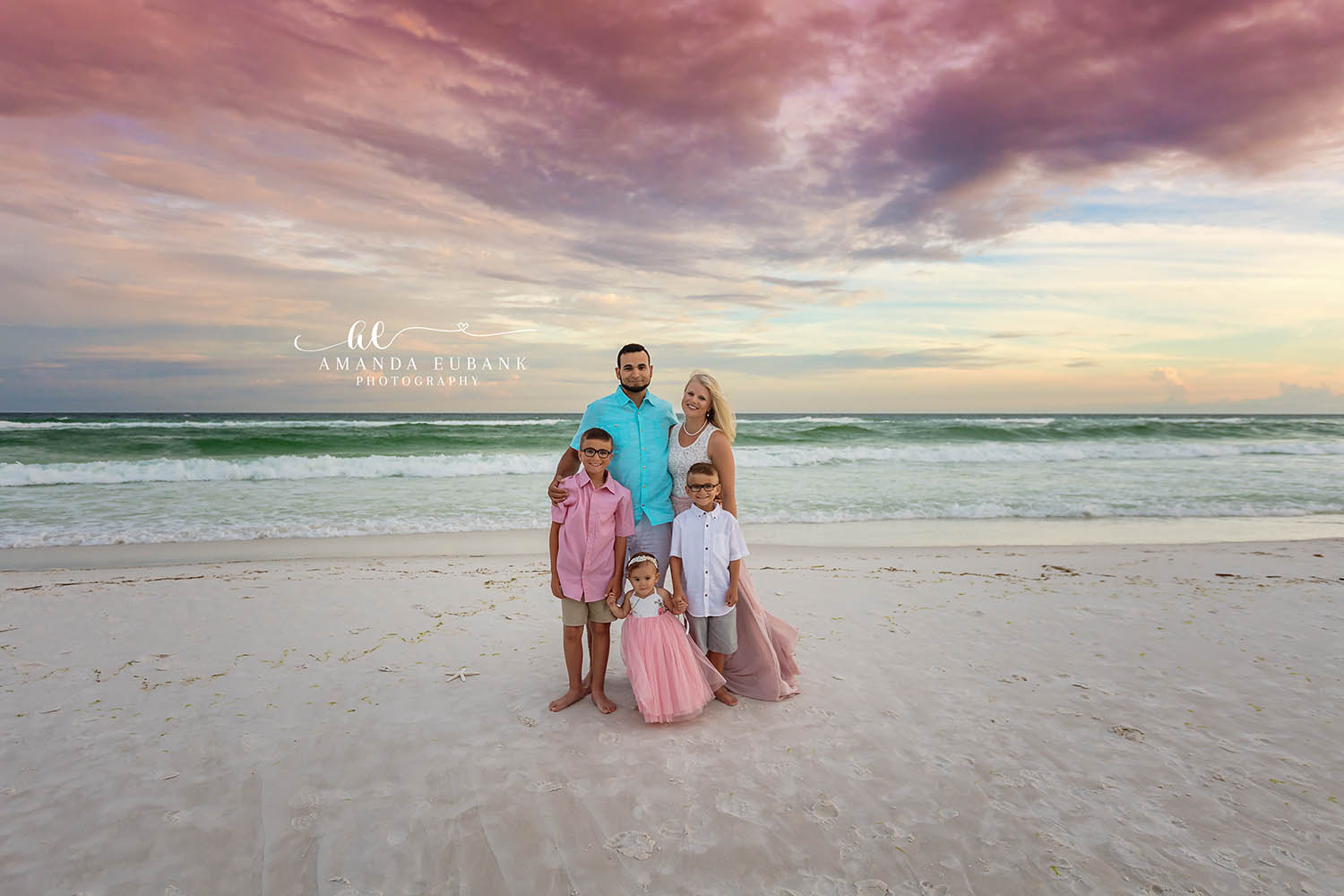 Family Under a Big Sky — Tampa, FL Family Session A family of six on the beach beneath a sweeping purple and gold cloudscape at a beach family session near Tampa, Florida.