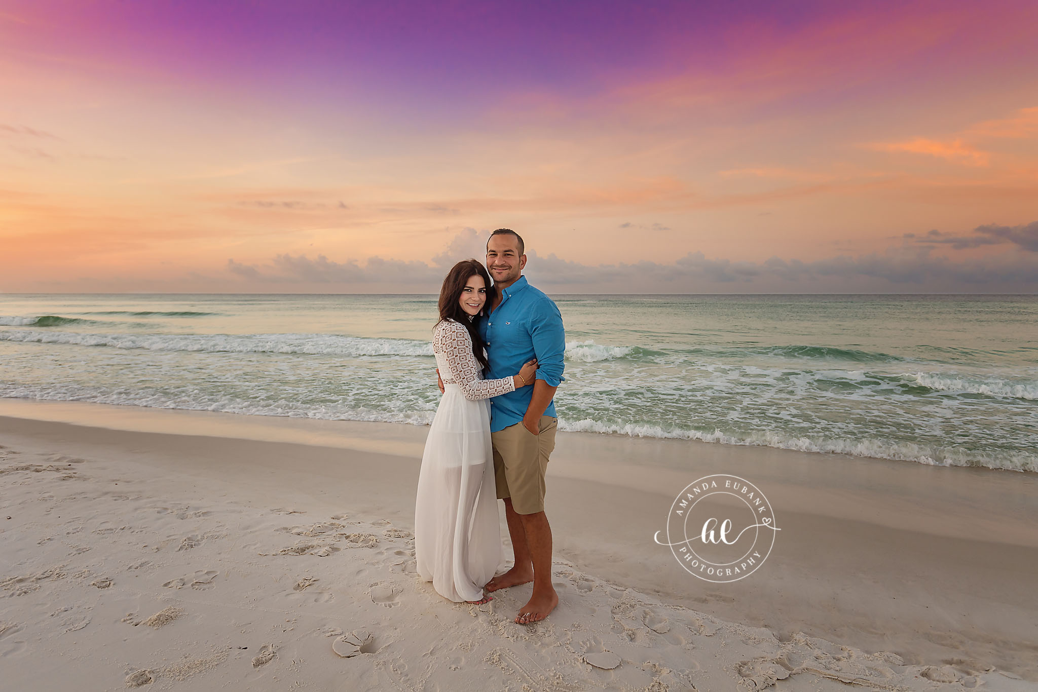 Couple in White and Blue | Couples Photographer in Tampa, Florida Couples portraits in Tampa, FL showing a couple embracing on the beach in a white maxi dress and blue shirt at sunset.