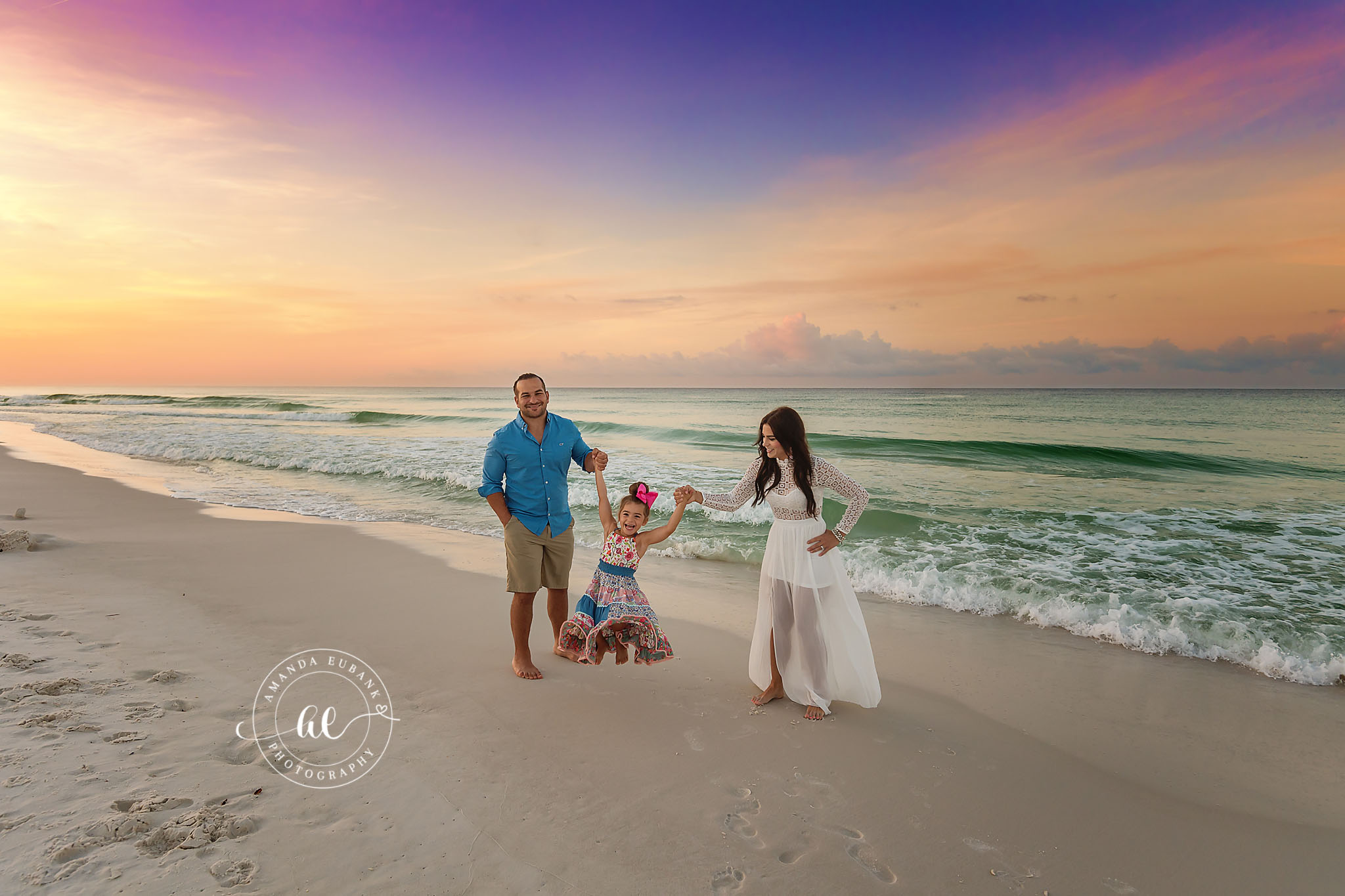 Family Walk at the Water’s Edge | Family Photographer in Tampa, Florida Family beach portraits in Tampa, FL showing a family of three walking together at the water's edge as the sun sets.