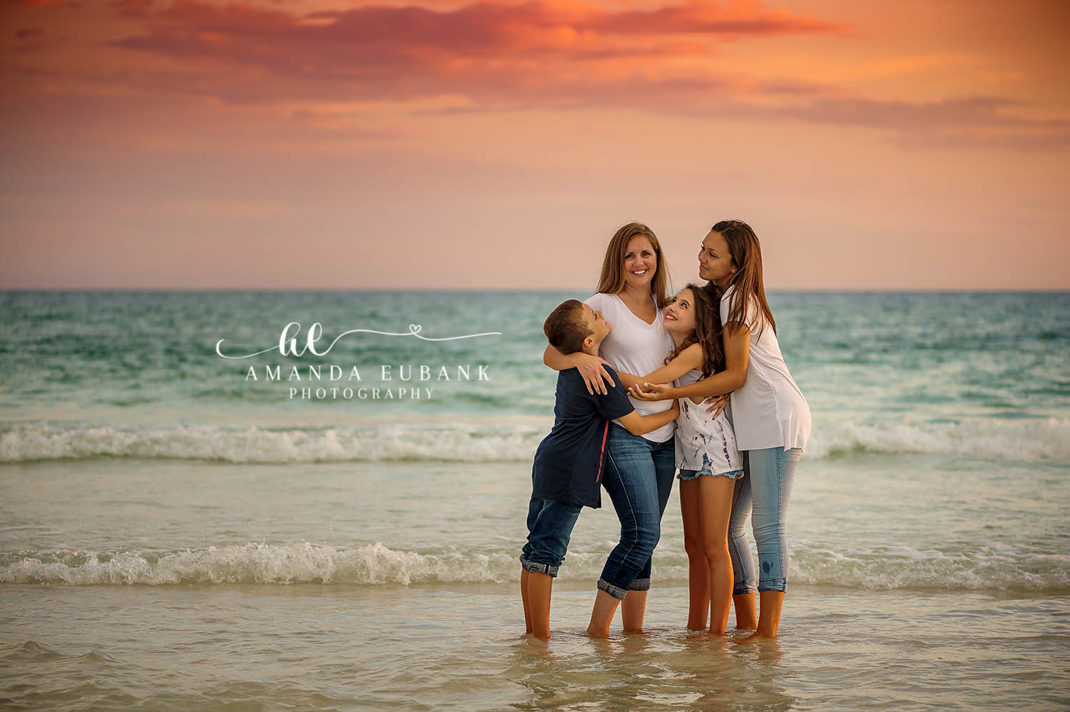 Mom and Teens in the Water | Tampa Family Photographer A mother and her two teenagers embracing in the shallow water at dusk during a Tampa family photography session.