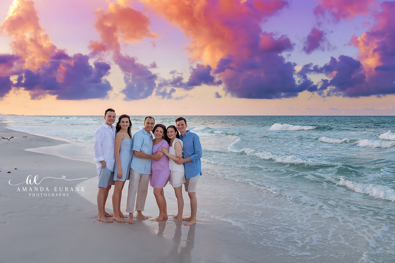 Family Under Purple Clouds | Family Photographer in Tampa, Florida Family beach portraits in Tampa, FL showing a family of six on the beach beneath towering purple sunset clouds.