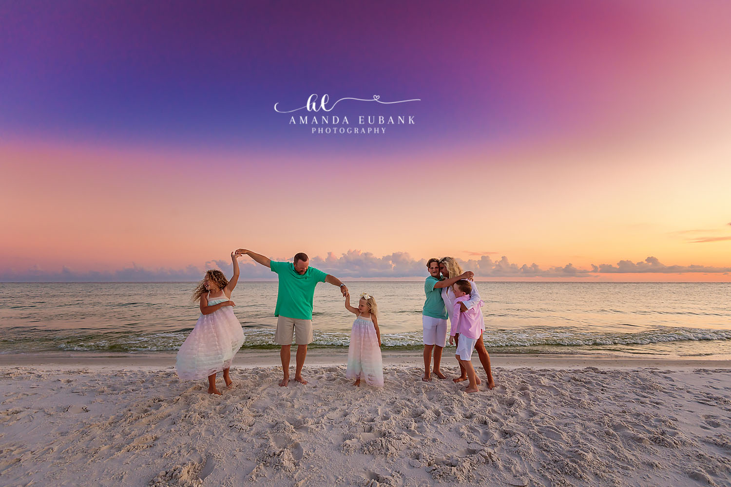 Twirling His Girls | Tampa Family Photographer A dad twirling his two daughters in tulle dresses on the sand at dusk during a Tampa family photography session.