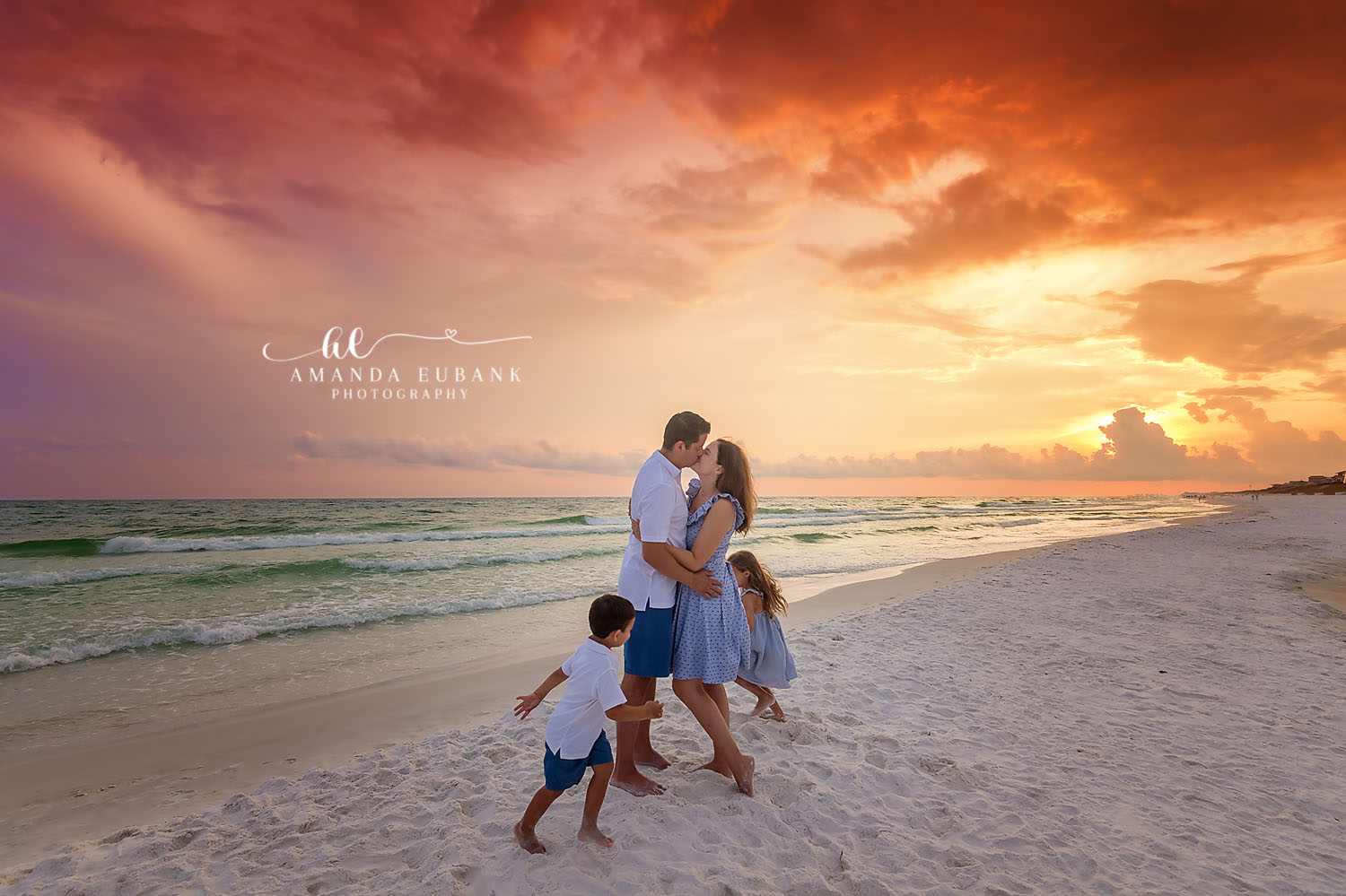 Parents Embrace at Sunset | Tampa Beach Family Photography Tampa family photographer captures a family of four on the beach with the parents embracing under a blazing sky.