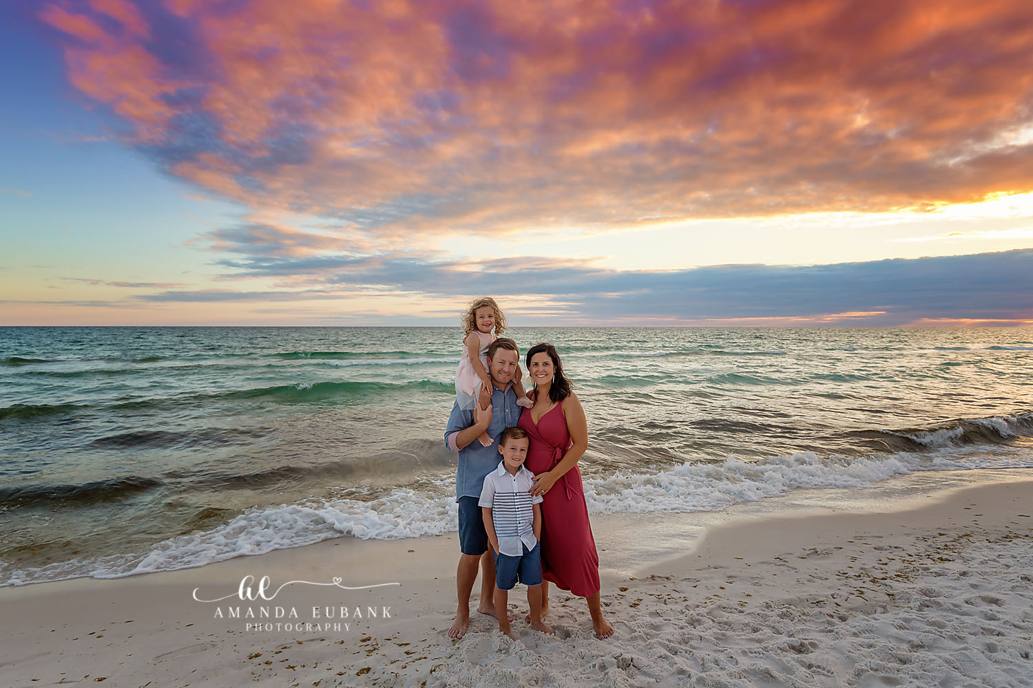Family in Red on the Shoreline | Tampa Family Photographer A family of five on the shoreline with mom in a red dress under dramatic clouds during a Tampa family photography session.