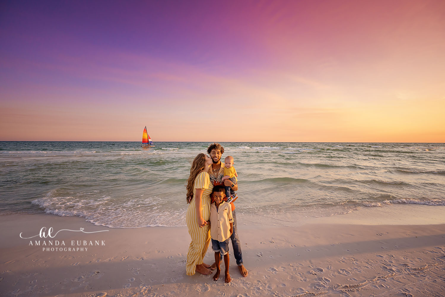Family in Yellow at Dusk | Tampa Family Photographer A family of four on the beach with mom in a yellow dress beside the aqua water during a Tampa family photography session.