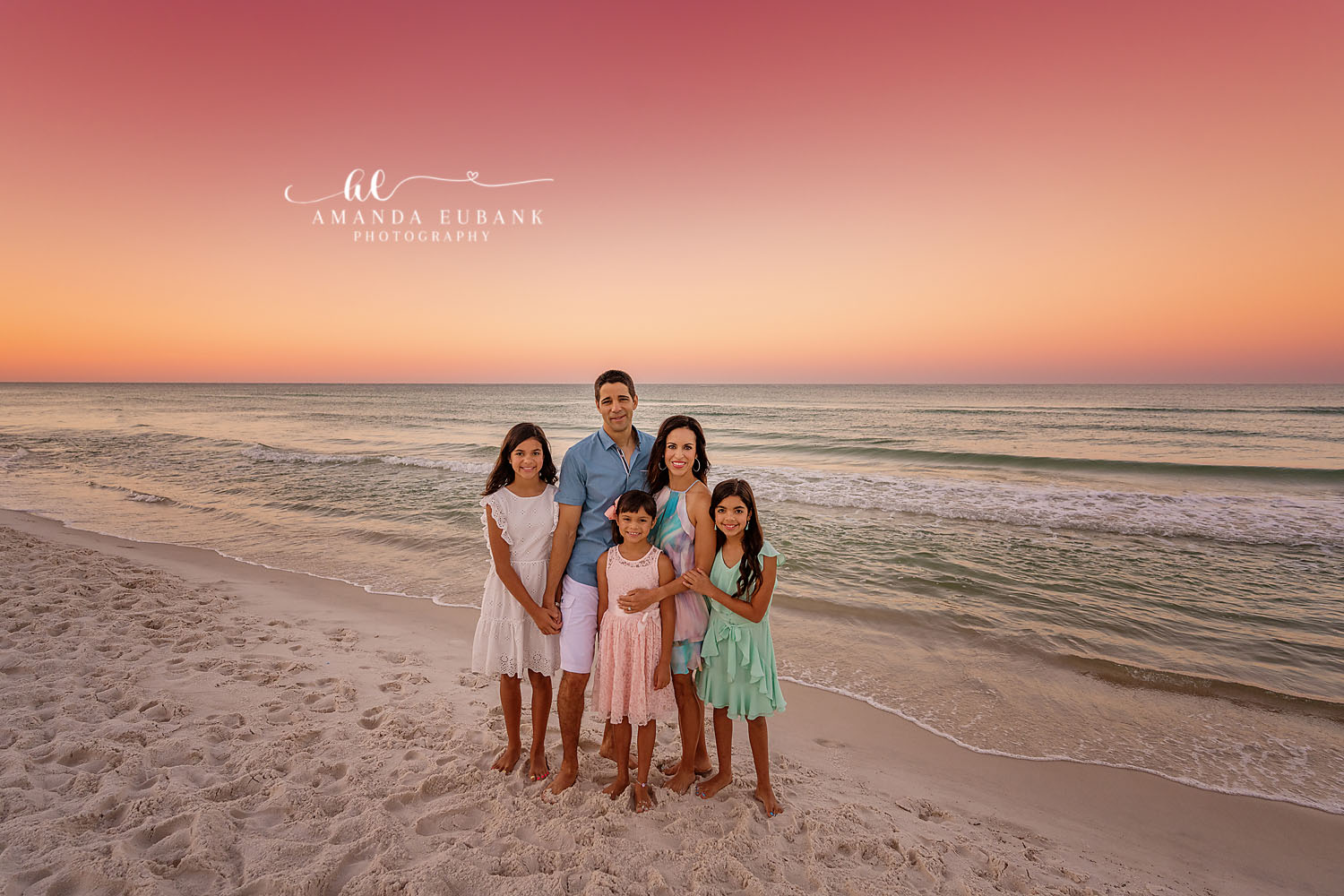 Family of Five on the Sand — Tampa, FL Family Session A family of five standing on the sand in white and blue under a coral sky at a beach family session near Tampa, Florida.