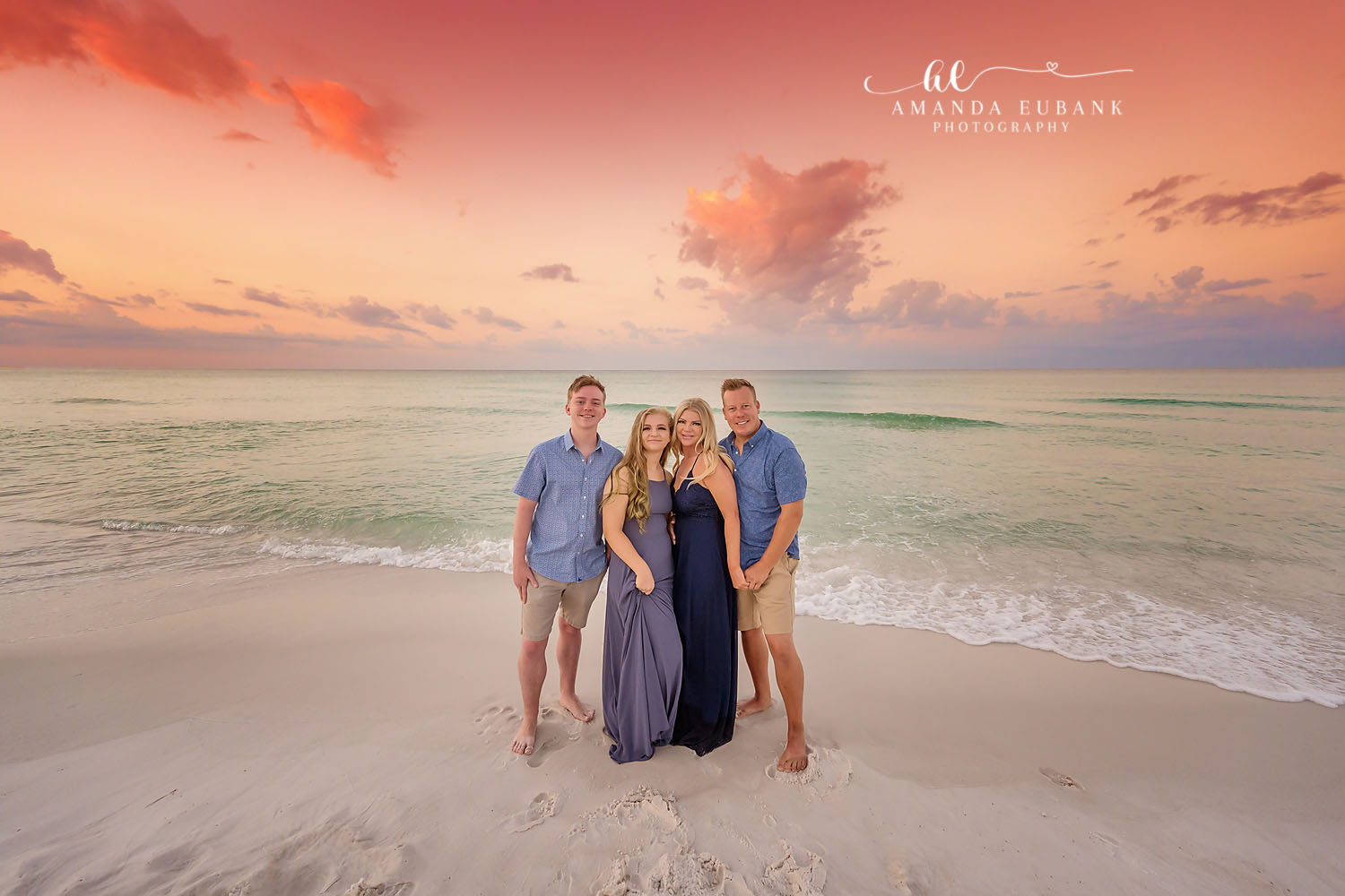 Family in Navy on the Sand | Family Photographer in Tampa, Florida Family beach portraits in Tampa, FL showing a family of four standing on the sand in navy and blue at pastel sunset.