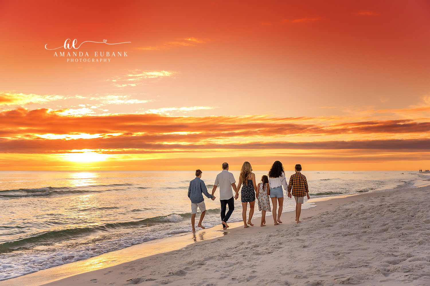 Sunset Walk Along the Water — Tampa, FL Family Session A family of six walking the shoreline with the sun low over the water at a beach family session near Tampa, Florida.