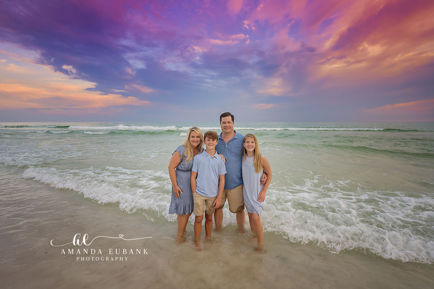 Family of Five in the Surf | Tampa Family Photographer A family of five standing in the shallow surf beneath violet clouds during a Tampa family photography session.