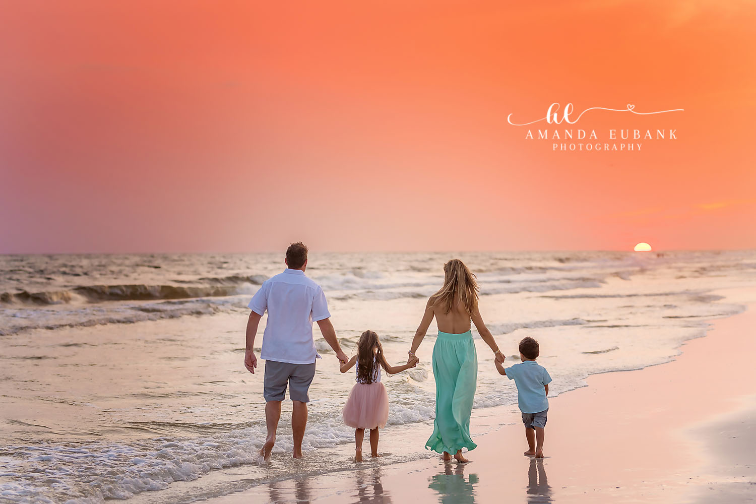 Walking Into the Sunset | Family Photographer in Tampa, Florida Family beach portraits in Tampa, FL showing a family of four walking hand in hand toward the setting sun.